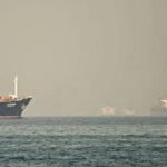 US Navy warship monitoring cargo vessel near Hormuz Strait during Iran USA maritime conflict